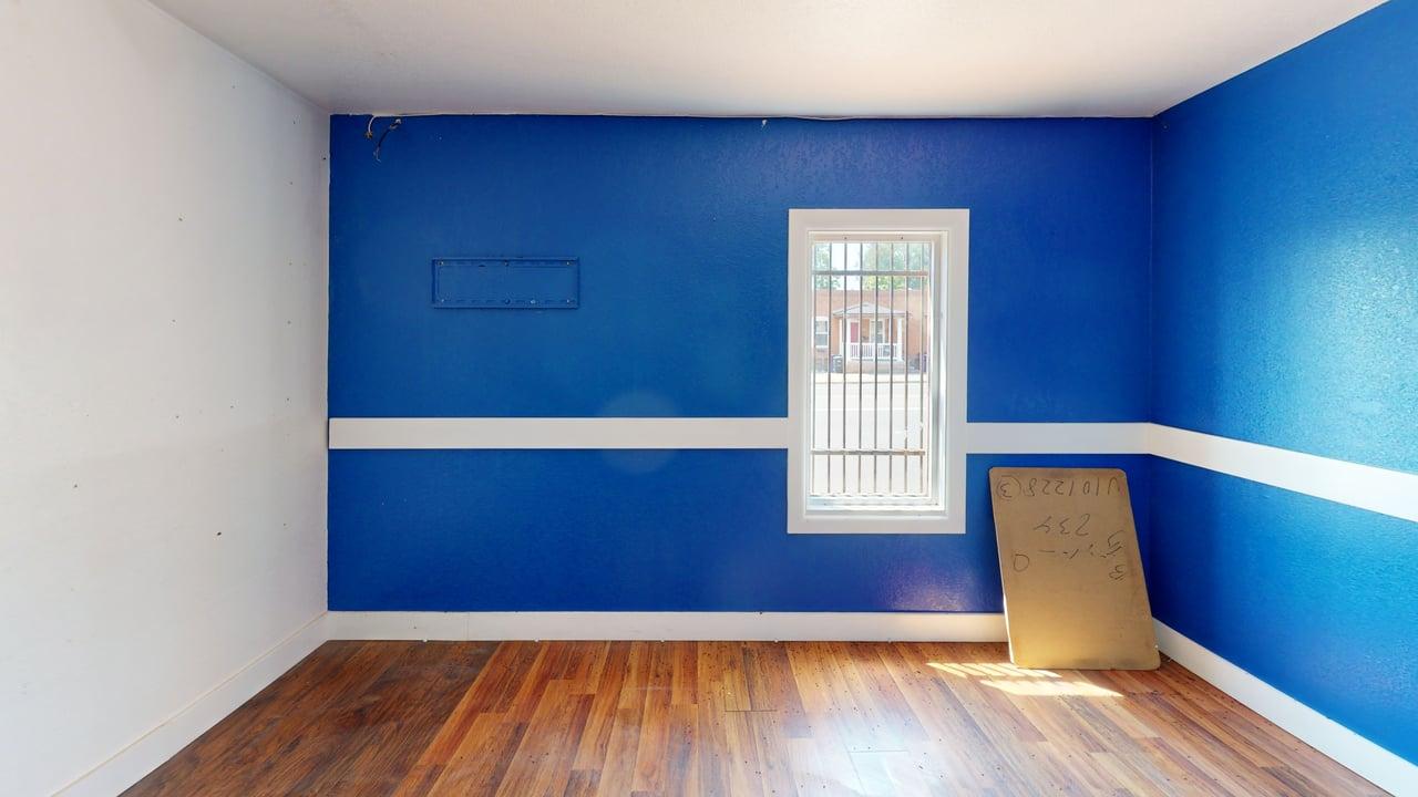 Room with hardwood floors, accent walls, and street-facing window